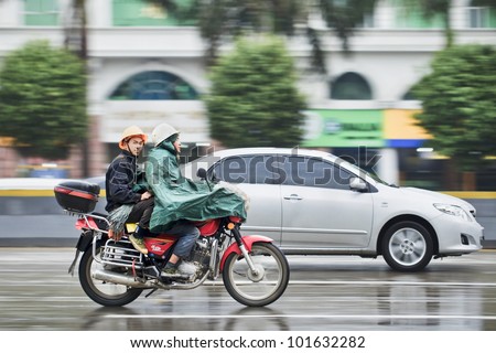 GUANGZHOU-FEB. 25, 2012. Motorcycle with passenger in the rain on Feb. 25, 2012 in Guangzhou. Guangzhou has an annual precipitation of 1982.7 mm, with rainfall concentrated in spring and autumn.