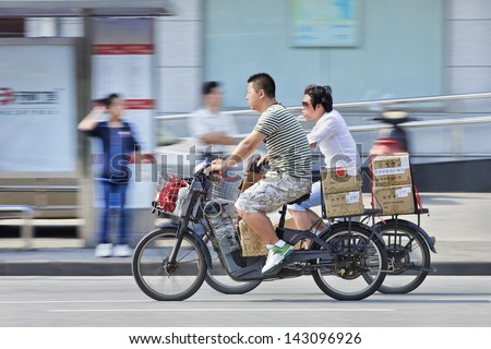 SHANGHAI-JUNE 3. Parcel delivery on e-bikes. At least 120 million e-bikes are already on Chinese roads, and sales are only growing thanks to a combination of falling prices. Shanghai, June 3, 2013.