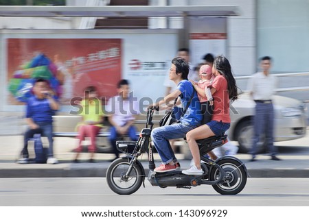 SHANGHAI-JUNE 3. Couple with their child on an electric bike. China\'s government family planning policy officially restricts married, urban couples to having only one child. Shanghai, June 3, 2013.