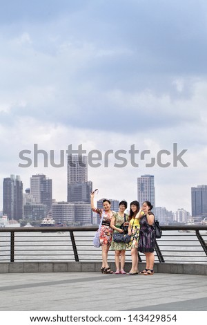 SHANGHAI-JUNE 6. Cheerful Chinese women at The Bund. It is a waterfront area, central Shanghai, which runs along the western bank of Huangpu River, facing Pudong area. Shanghai, June 6, 2013.