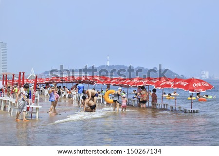 YANTAI-CHINA-JULY 17. Chinese beach with Coca-Cola parasols. Coca-Cola has been in China since 1927 and is now one of its top 20 brands. The brand will invest $4bn expanding. Yantai, July 17, 2013.