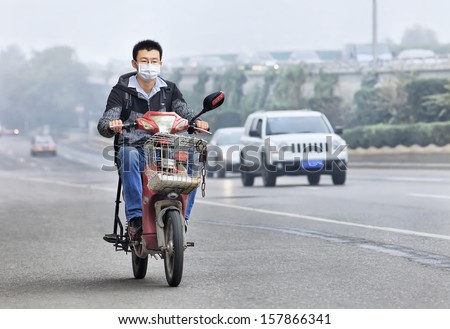 Beijing- Oct. 6. Young Man On An E-Bike Covers His Mouth Against Smog. Monitoring At Us Embassy Showed The Beijing Air Has Been Very Unhealthy Or Hazardous First Week October. Beijing, Oct. 6, 2013.