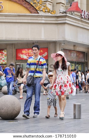 SHANGHAI - JUNE 6. Couple with their child at shopping area. With a population of over 1.3 billion and dwindling natural resources, China is concerned and has a one-child policy family planning.