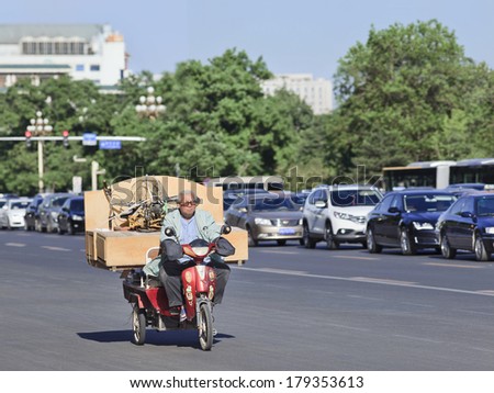 BEIJING-MAY 29, 2013. Chinese elderly transports a cabinet and folding bicycle on his e-bike. The number of electric-powered bicycles all over China just passed the 200 million mark.