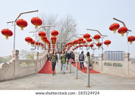 BEIJING-MARCH 24, 2014. Two young girls on a bridge with red lanterns. Young Chinese are crazy for western culture whereas they tend to neglect preservation and inheritance of their native culture.