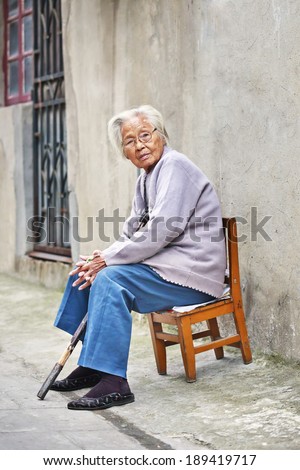 YANGZHOU, CHINA-SEPT. 25, 2010. Old Chinese woman sit outside on a chair. The elderly population (60 years or older) in China is 128 million or one in every ten people, the largest in the world.