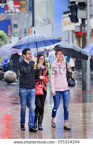 SHANGHAI-MAY 4, 2014. Caucasian couple and Chinese girl with umbrella in city center. Shanghai has humid subtropical climate, summer is warm and humid, with occasional downpours or thunderstorms.