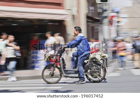 SHANGHAI-MAY 3, 2014. man on electric bike. In just a decade, Chinese e-bikes increase from near zero to over 150 million, the largest adoption of an alternative fuel vehicle in motorization history.