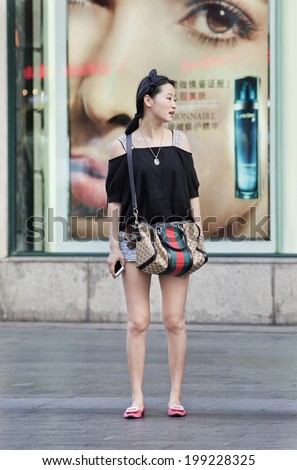SHANGHAI-JUNE 5, 2014. Fashionable Chinese woman in front of cosmetics store. China's cosmetics market is worth $26 billion a year, the third-biggest in the world, it grows 8% annually until 2017.