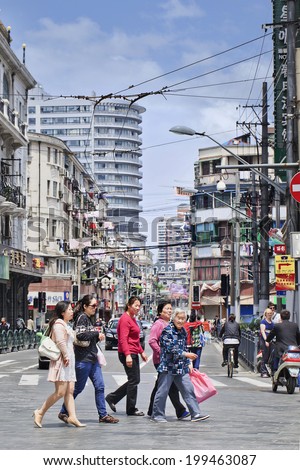 SHANGHAI-MAY 5, 2014. Women crossing street in dense area. Urban densities average around 40,000 residents per square KM in core districts, 760 persons per hectare in Huangpu central neighborhood.