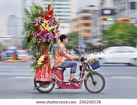 KUNMING-JULY 5, 2014. Flower transport on an electric bike. Motorized bikes in Chinese cities became a rarity, the number of electric-powered bicycles in China has just passed the 200 million mark.