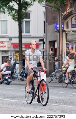 AMSTERDAM-AUG. 19, 2012. Cycling man at Dam Square. 38% of the traffic movement in the city is by bike, 37% by car, 25% by public transport. In the center, 57% of traffic movement happens by bike.