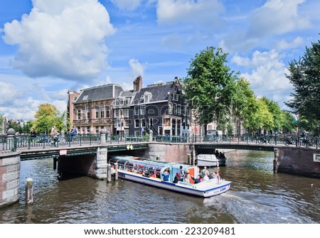 AMSTERDAM-AUG. 24, 2014. Ancient bridges, canal and a tour-boat. Amsterdam is known as Venice of the North, it has 1,200 bridges and 165 canals. Best way to experience them is one of the boat tours.