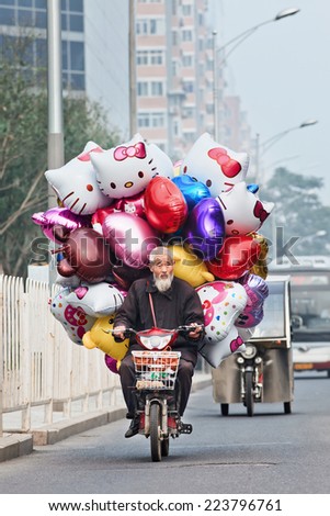 BEIJING-OCT. 11 ,2014. Vendor on an e-bike with balloons. Government employees often harass, beat and extort money from street vendors. Their official name is chengguan, which means city management.
