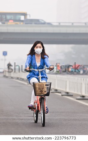 BEIJING-OCT. 11 ,2014. Girl on a bicycle in smog blanketed city. A concentration of PM2.5, small particles that poses a huge health risk, hit 462 according U.S. Embassy pollution monitor in Beijing.