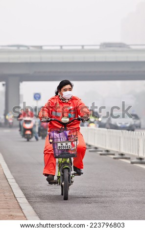 BEIJING-OCT. 11 ,2014. Female worker on e-bike in smog blanketed city. A concentration of PM2.5, small particles that poses a huge health risk, hit 462 according U.S. pollution monitor in Beijing.