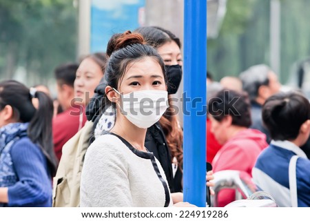 BEIJING-OCT. 19, 2014. Chinese girl with a face mask. Beijing raised its smog alert to orange because the air quality is a health threat. Face masks, once a rarity in Beijing, have now become common.