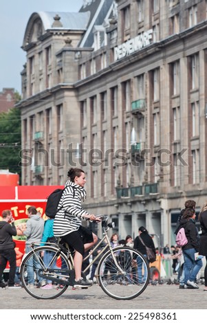 AMSTERDAM-AUGUST 26, 2014. Caucasian woman cycling on the Dam Square. Amsterdam is known as one of the most bicycle-friendly cities in the world. 38% of all journeys in the city are made by bicycle.