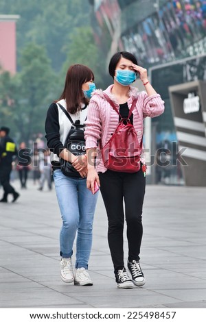 BEIJING-OCT. 19, 2014. Face masked girl gets dizzy from smog. Beijing raised its smog alert to orange because the air quality (concentration of PM2.5 small particles) became a human health threat.