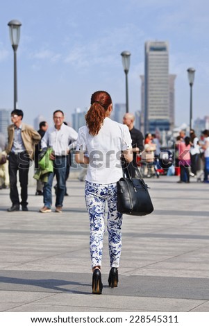 SHANGHAI-MAY 5, 2014. Fashionable Chinese girl walks on the Bund boulevard. After Milan, Paris, London and New York, Shanghai is going to claim and candidate to become the Oriental Fashion Capital.