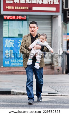 CHONGQING-NOV. 4, 2014. Father carry his young son. After 30 years of Chin's one child policy, many families won't take advantage of allowing a second child because of rising cost of child-rearing.