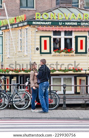 AMSTERDAM-AUGUST 26, 2014. Couple having romantic time near tour-boat starting point. Its historic canal belt with lovely ancient houses, canals and bridges is a romantic experience for many people.