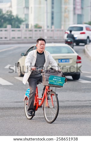 WENZHOU-NOV. 17, 2014. Man on rental bike. China has currently over 50 public bike sharing projects, dwarfing all other nations. Chinese cities effort to integrate bike sharing with public transport.