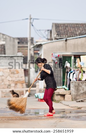 WENZHOU-NOVEMBER 17, 2014. Woman sweeps with a broom. Lives of women in China have significantly changed after government made efforts towards gender equality in a traditional male-dominated society.