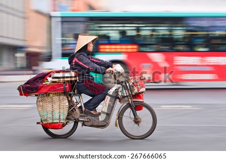 KUNMING-JULY 5, 2014. Woman transports stuff on electric bike. Motorized bikes in Chinese cities became a rarity, the number of electric-powered bicycles in China has just passed the 200 million mark.