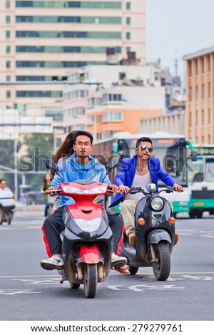 KUNMING-JUNE 30, 2014. Cool guys on e-bikes. An estimated 200 million Chinese now use e-bikes, 1,000-fold increase from 15 years ago. About 90 percent of world\'s e-bikes were sold in China in 2012