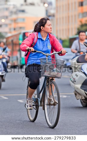 KUNMING-JUNE 30, 2014. Middle woman cycles in city center. With a population of 1,342,700,000, 500,000,000 bicycles and 37.2 cyclists China is still the number one bicycle country in the world.