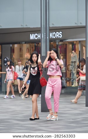 BEIJING-JULY 25, 2014. Fashionable girls at the Village shopping area. Past decade, China\'s economic boom has dominated global fashion. Global brands saw China as the future market when it opened up.