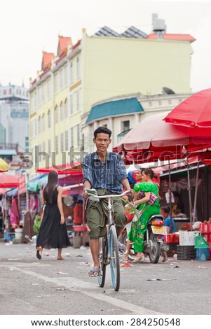 RUILI-CHINA-JUNE 28, 2014. Tanned man cycles on a local market. Ruili is on the border with Myanmar, 64% of population are members of five ethnic minorities including Dai, Jingpo, Deang, Lisu, Achang.