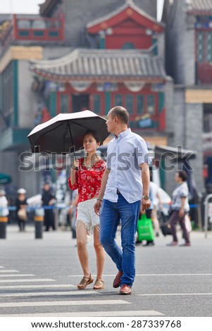 BEIJING-JUNE 9, 2015. Young woman with a parasol as sun protection. Since ancient times a pale skin is an absolute Chinese beauty ideal. A tanned skin is often associated with low class labors.