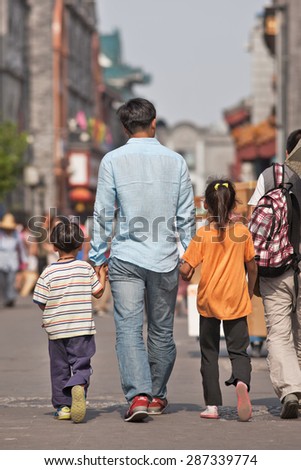 BEIJING-JUNE 9, 2015. Young father with his two children. Although China has relaxed its one-child policy late 2013, the number of Chinese families having more than one child is still relatively low.