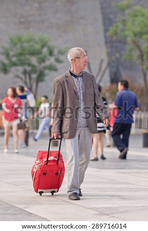 BEIJING, CHINA -JUNE 9, 2015. Old man with suitcase at Qian Men. Elderly population (60 or older) in China is 128 million, one in every ten people, the world\'s largest. China has 400 million elderly by 2050.