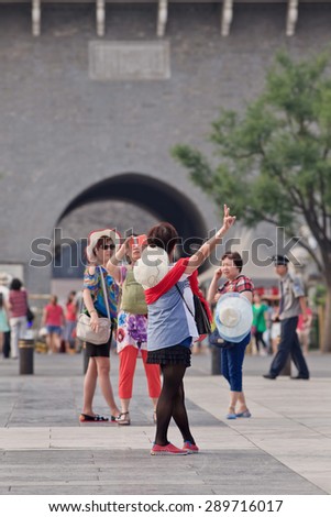 BEIJING, CHINA -JUNE 9, 2015. Woman takes photos with her smart phone at Qian Men. China has currently 519.7 million smartphone users. That figure will rise to 574.2 million Chinese smartphone users by 2015.