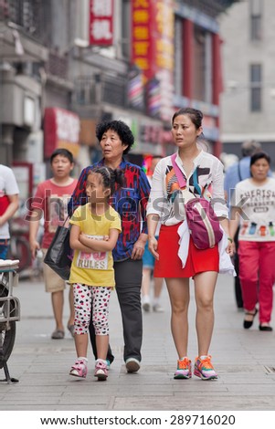 BEIJING, CHINA -JUNE 9, 2015. Young woman with her daughter and mother. In order to help their children pursue professional goals, older Chinese people often take an active role in raising grandchildren.