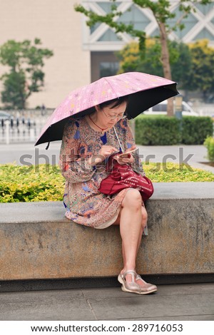 BEIJING, CHINA -JUNE 16, 2015. Middle-aged woman busy with her smartphone. China has currently 519.7 million smartphone users but that figure will rise to 574.2 million Chinese smartphone users by 2015.