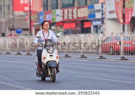 BEIJING-JULY 10, 2015. Woman on an e-bike. In a decade, e-bikes in China climbed from near zero to over 150 million (2015), the largest adoption of alternative fuel vehicle in history of motorization