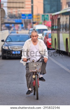BEIJING-JULY 10, 2015. Chinese senior on a bicycle. Although the fast multiplication of cars in China the bicycle remains the biggest means of individual mobility for hundreds of millions Chinese.