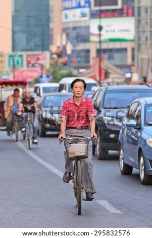 BEIJING-JULY 10, 2015. Middle aged man on a bicycle. Although the fast multiplication of cars in China the bicycle remains the biggest means of individual mobility for hundreds of millions Chinese.