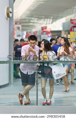 BEIJING-JULY 18, 2015. Couple busy with smart phone in a shopping mall. China has currently 519.7 million smartphone users. That figure will rise to 574.2 million Chinese smartphone users by 2015.