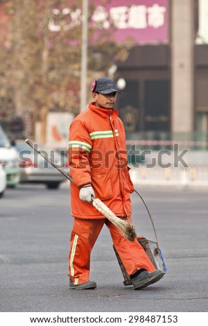 BEIJING-DECEMBER 4, 2012.  Street sweeper in orange work wear walks on the street. Thanks to an army of street sweepers the Beijing city center is currently one of the cleanest of the country.