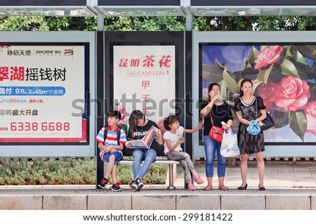 KUNMING-JULY 5, 2014. People at bus stop with advert. China\'s outdoor advertising market grows annually more than 23% since 2000, versus 17% for overall ad market, 14% for TV and 16% for newspapers.