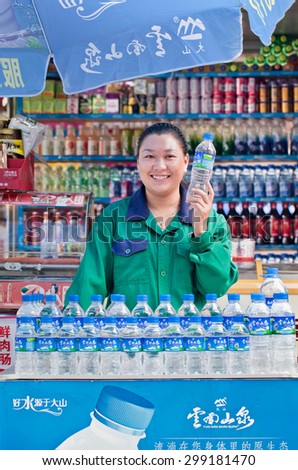 KUNMING-JULY 1, 2014. Girl in a stall with soft drinks and water. Water quality is a major concern in China due to pollution. Water from water tap is not drinkable, so dwellers rely on bottled water.