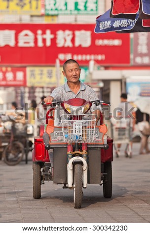 BEIJING-JULY 24, 2015. Elderly on electric trike. In a decade, e-bikes in China climbed from near zero to 150 million (2015), largest adoption of alternative fuel vehicle in history of motorization.