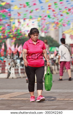 BEIJING-JULY 24, 2015. Overweight middle aged woman in shopping area. China\'s obesity rate has skyrocketed over last decades, resulting in 46 million obese Chinese adults and 300 million overweight.