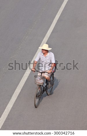 BEIJING-JULY 24, 2015. Elderly on a rusty bicycle. Although the fast multiplication of cars in China the bicycle remains the biggest means of individual mobility for hundreds of millions Chinese.