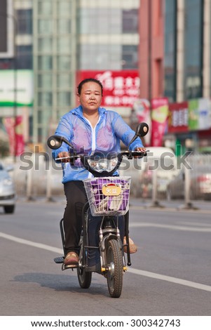 BEIJING-JULY 24, 2015. Female elderly on e-bike. In a decade, e-bikes in China climbed from near zero to 150 million (2015), the largest adoption of alternative fuel vehicle in history of motorization